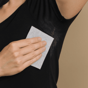 Using a cloth to wipe away white deodorant marks on a black shirt