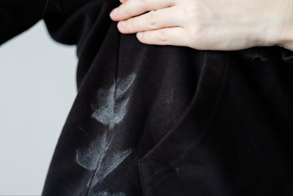 White deodorant stains on the underarm area of a black shirt