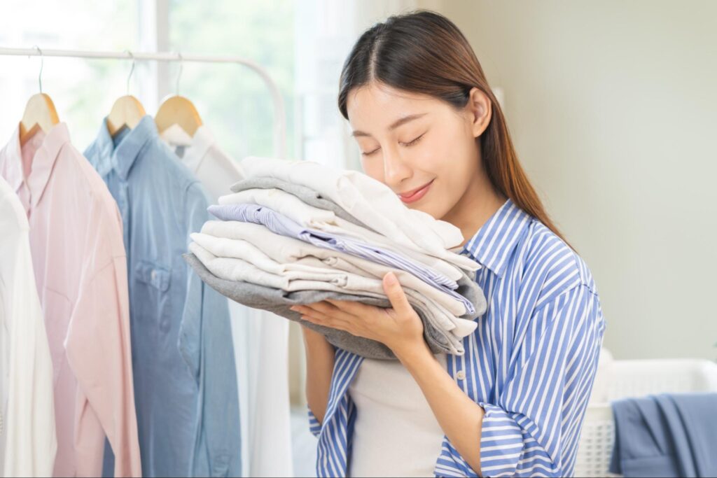 holding up a sweaty t-shirt and smelling it before laundry