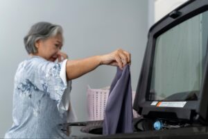 placing smelly workout clothes into a washing machine