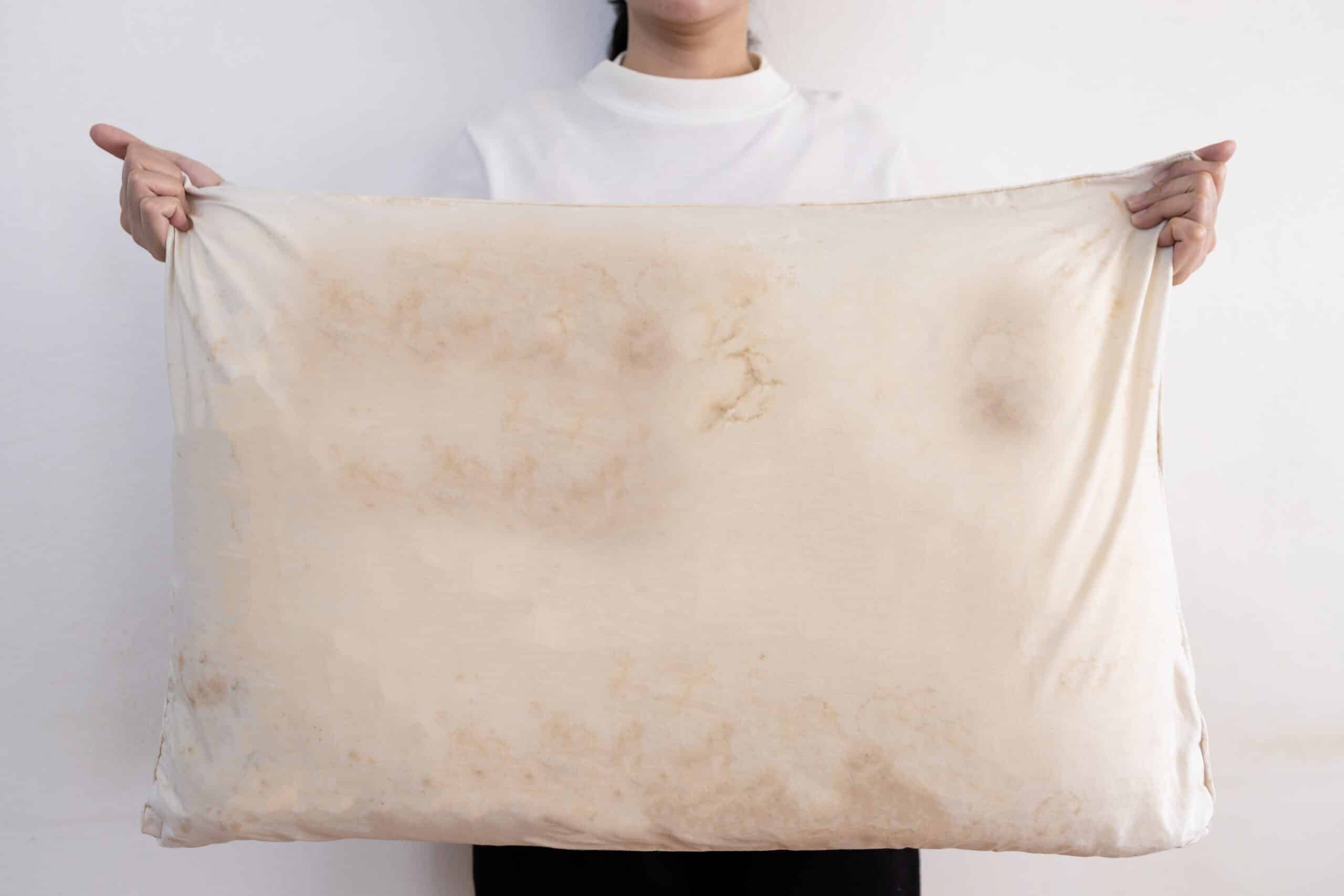 Woman holding dirty pillow with stains