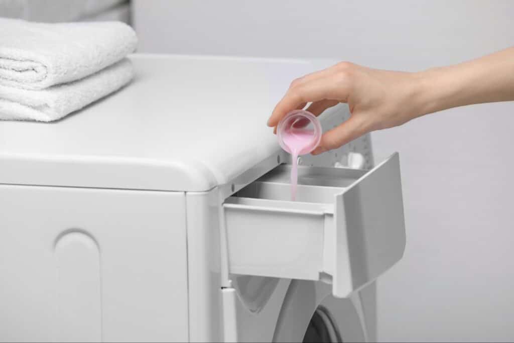Pouring liquid fabric softener into a washing machine dispenser
