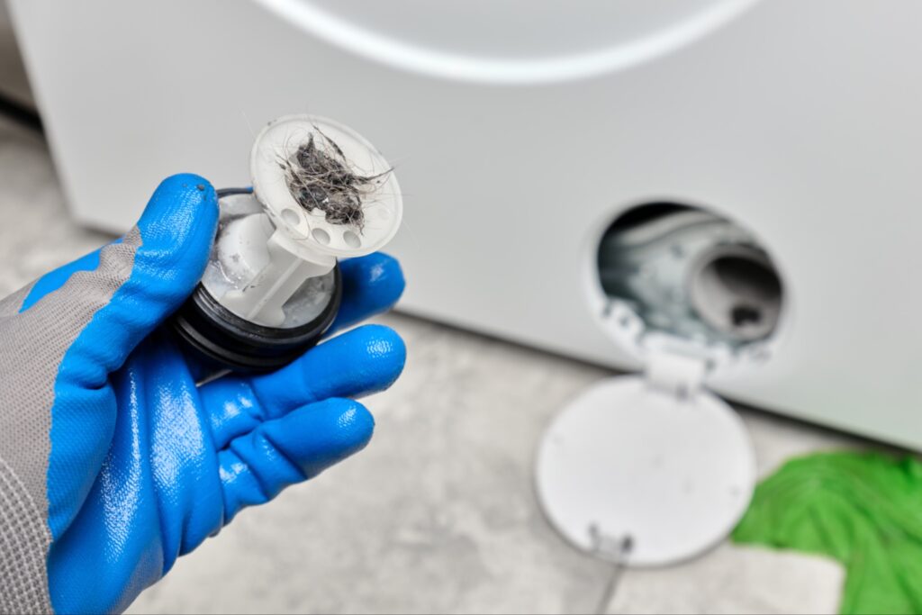 Open washing machine filter compartment at the bottom of a front-load washer