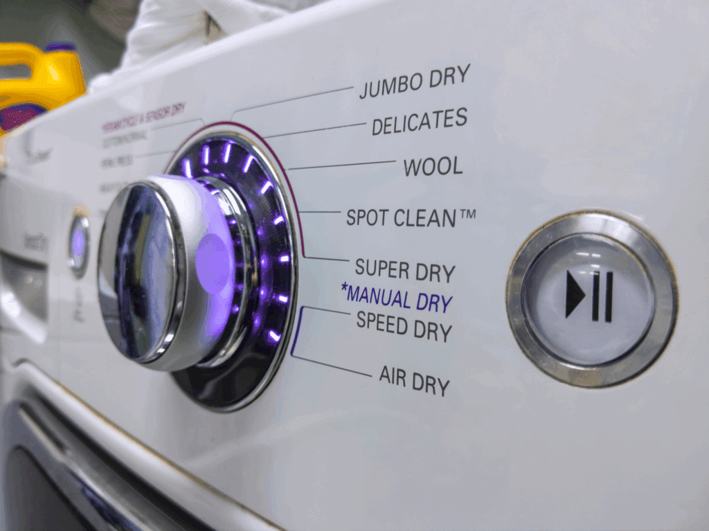 Close-up of a dryer control panel set to a low heat, delicate cycle for dark garments