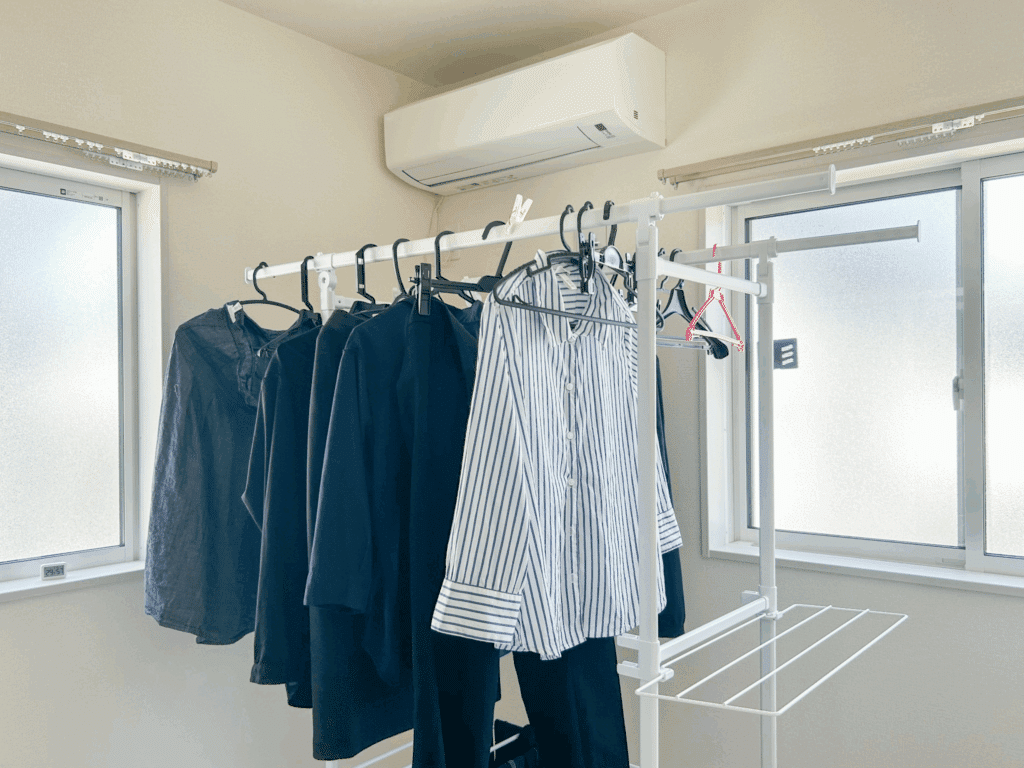Dark shirts and pants hanging on an indoor drying rack, kept away from direct sunlight