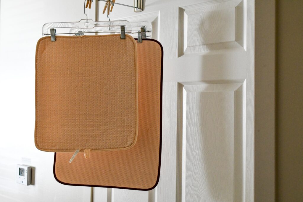 A rubber-backed rug hanging outside on a clothesline to air dry in the sun