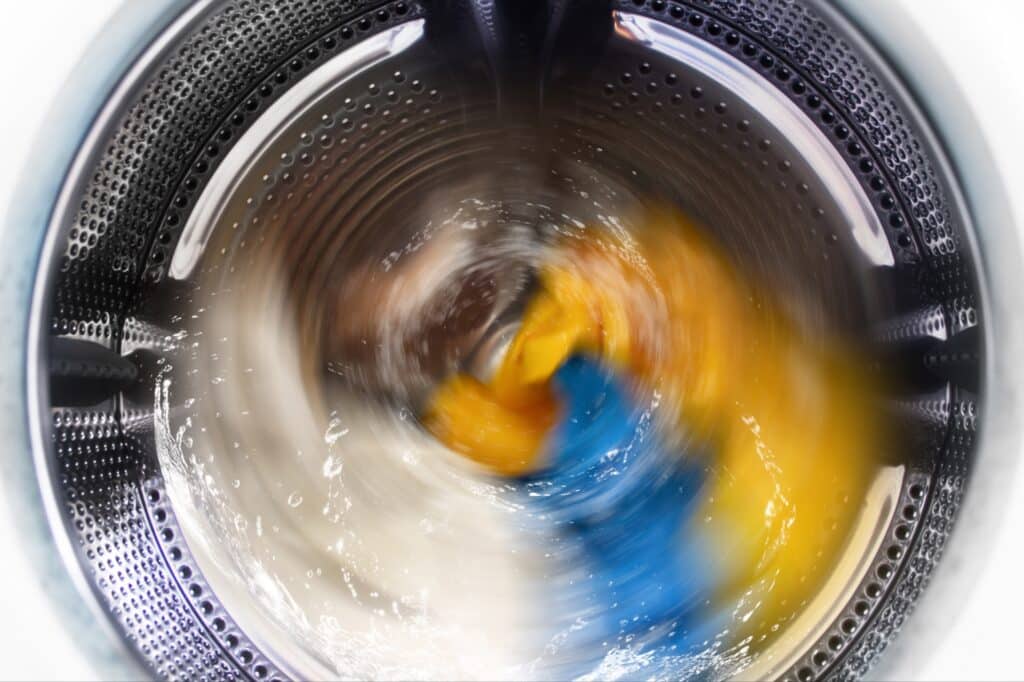 A top-loading washing machine running on a heavy soil cycle with vigorous agitation and plenty of water