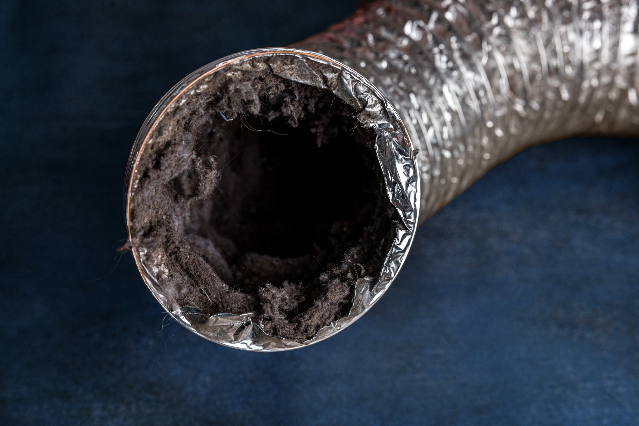 Close-up of a lint-clogged dryer vent tube filled with fuzz and debris