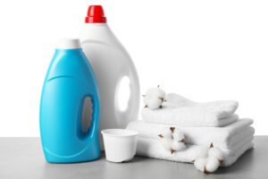 Laundry detergent bottles and folded white towels arranged on a clean surface