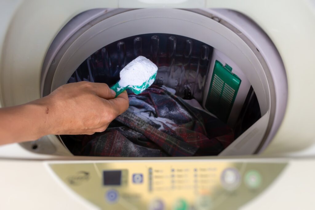 Adding a measure of washing soda into a washing machine to boost detergent and tackle heavy stains