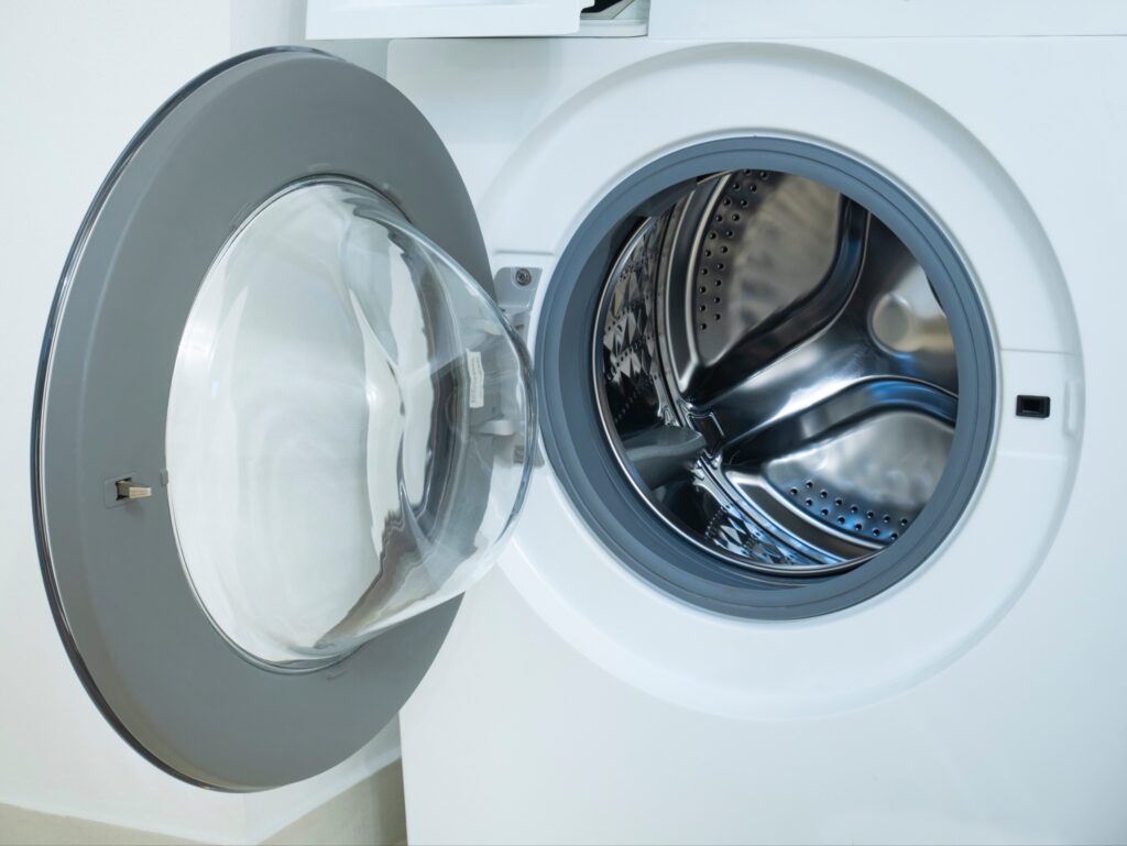 A modern front-load washing machine with the door left open after a wash, allowing it to air dry and prevent odor buildup