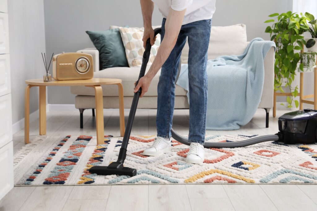 Vacuuming a patterned area rug in a living room
