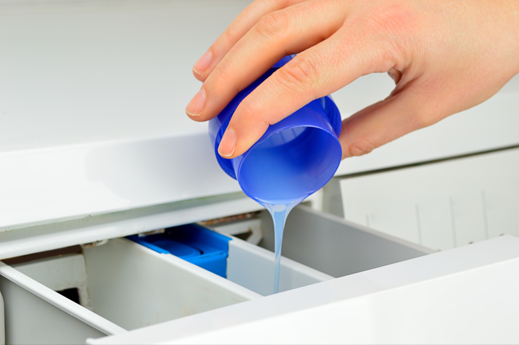 Liquid laundry detergent being poured into a washing machine detergent drawer