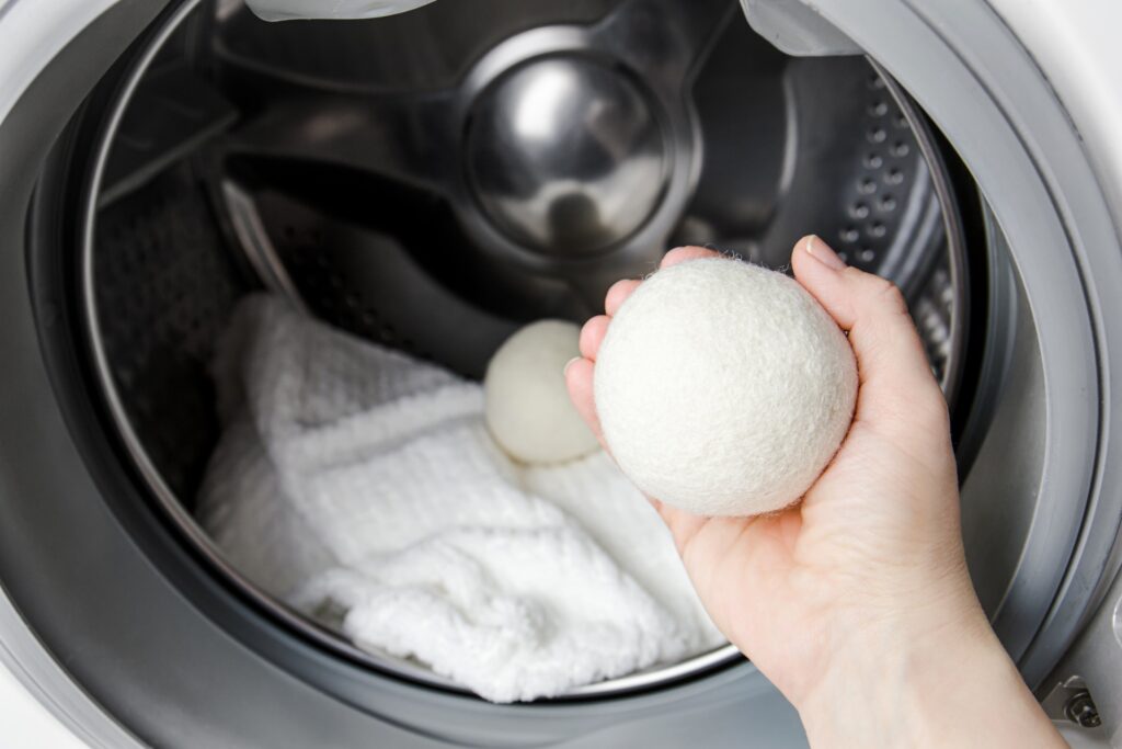 Hand holding a wool dryer ball inside a dryer drum