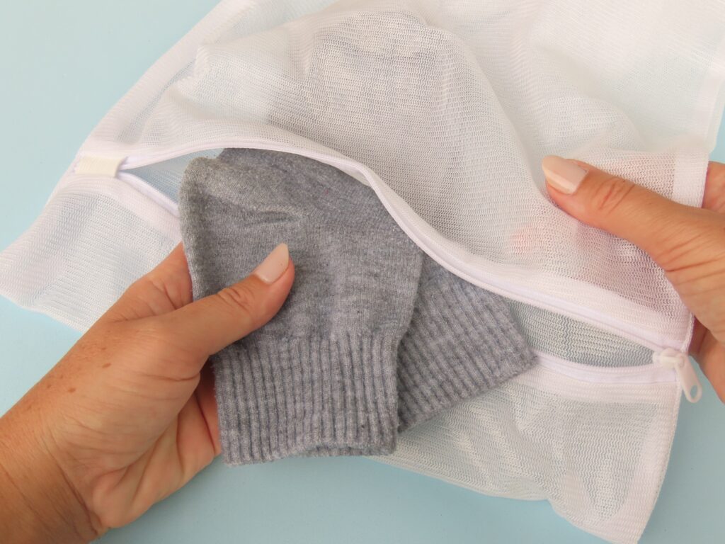 Hands placing socks into a mesh laundry bag