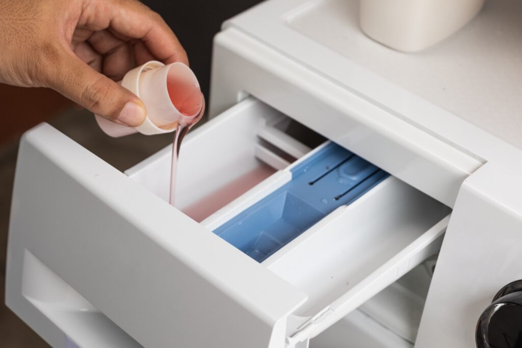 Liquid detergent being poured into a washing machine drawer