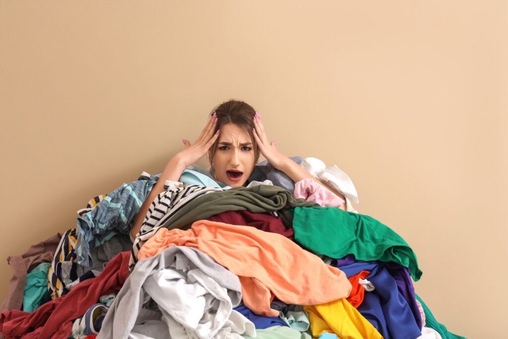 Overwhelmed parent sitting behind a pile of laundry