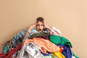 Overwhelmed parent sitting behind a pile of laundry