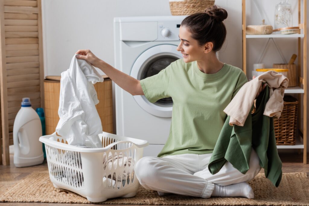 Person sorting laundry into a basket in front of a washing machine