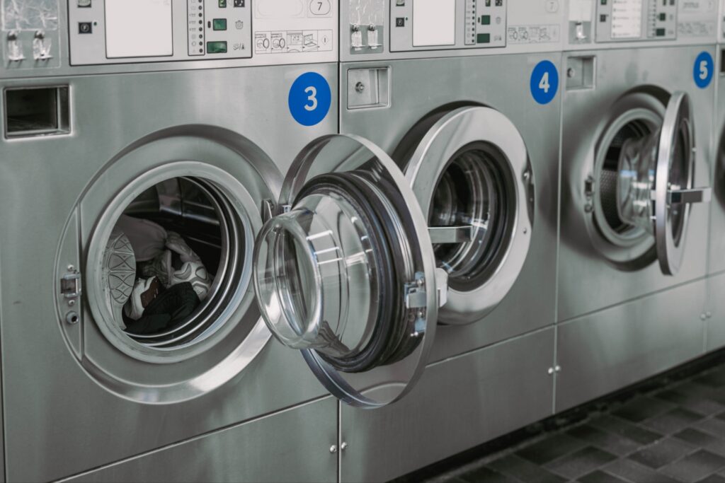 Row of commercial washing machines with doors open