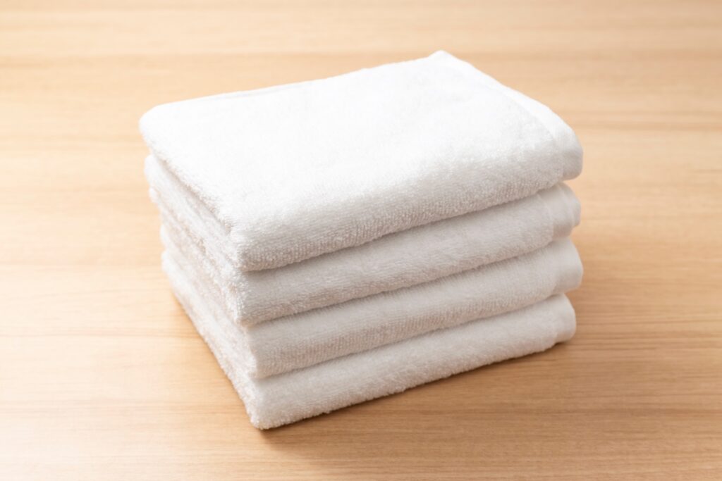 Stack of folded white towels on a wooden surface